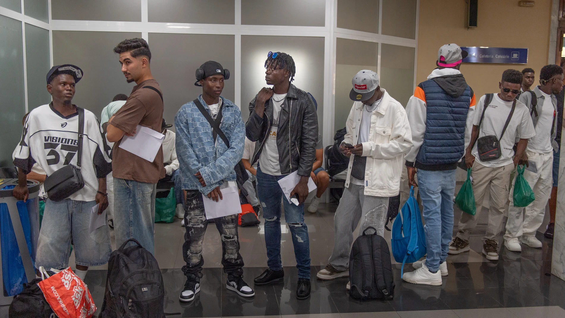Un grupo de personas hacen cola en el Puerto de Ceuta, antes de ser trasladados a la península, a 14 de agosto de 2025, en Ceuta (España). Un total de 47 personas migrantes, todas ellas varones, han partido desde el Centro de Estancia Temporal de Inmigrantes (CETI) de Ceuta rumbo a la península. Con esta salida, las instalaciones de acogida para adultos en la ciudad autónoma quedan con alrededor de 600 personas alojadas, unas 80 por encima de la capacidad oficial del centro, gestionado por la...