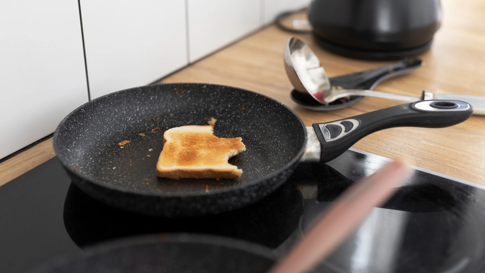 Una tostada quemada en la sartén de teflón que puede contener PFAS sobre una vitrocerámica en una cocina