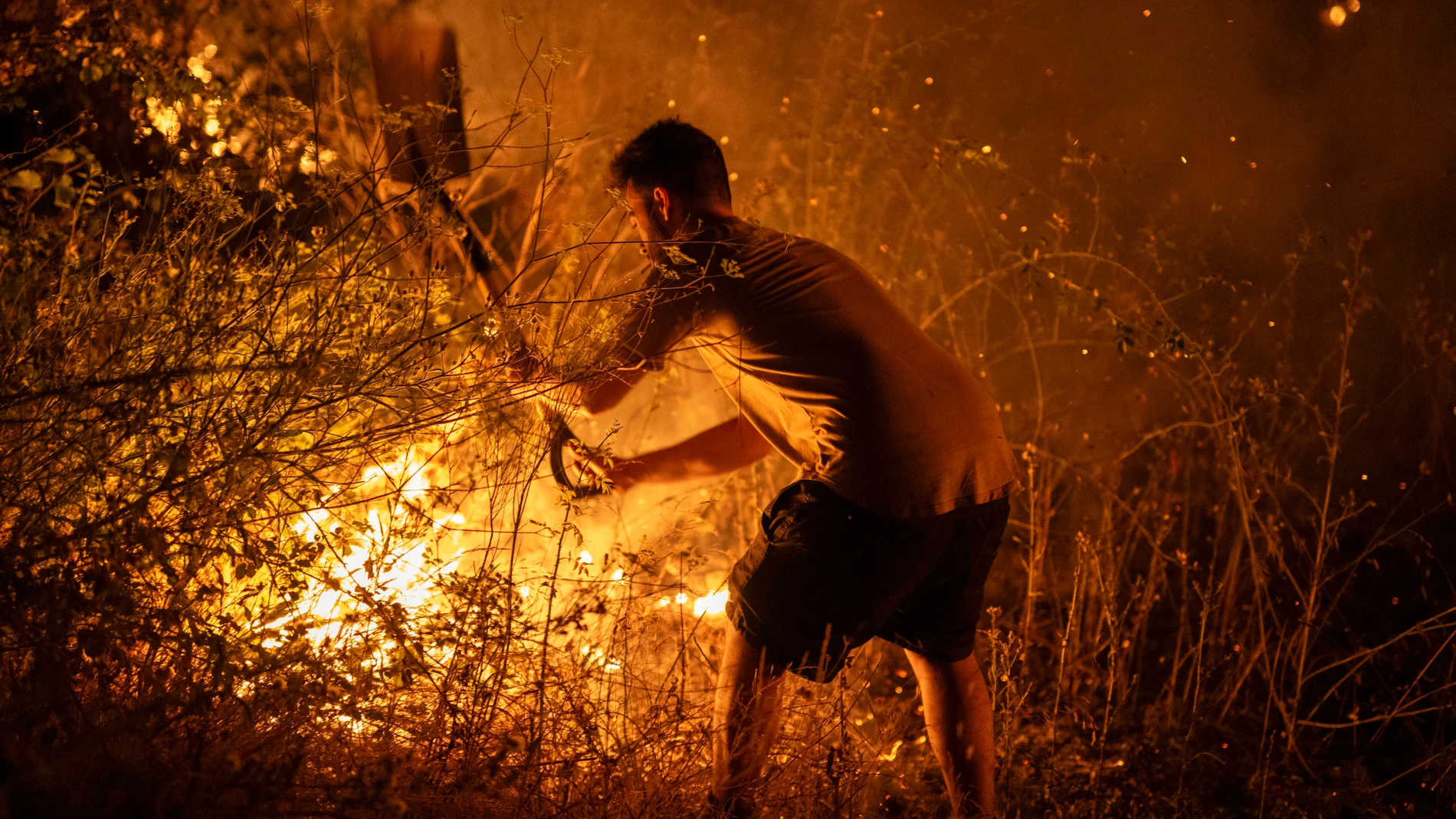 FOTODELDÍA - A RÚA (OURENSE), 17/08/2025.- Un vecino trabaja la madrugada de este domingo en labores de extinción del incendio forestal de A Rúa (Ourense). Los incendios han calcinado más 50.000 hectáreas, la mayoría en la provincia de Ourense, la más castigada por el momento y en la que se han reactivado fuegos en las últimas horas. EFE/Brais Lorenzo