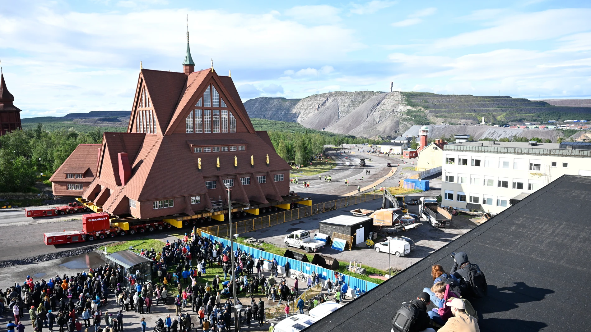 KIRUNA (Sweden), 19/08/2025.- People watch as the Kiruna Church landmark is being moved on a specially designed trolley with 224 wheels at a speed of half a kilometer per hour in Kiruna, northern Sweden, 19 August 2025. The 40-meter-wide, 672,000-kilo wooden church has been placed on a wheeled trailer for its five-kilometre relocation to Kiruna's new town center on 19 and 20 August, due to the expansion of the iron ore mine. (Suecia) EFE/EPA/Fredrik Sandberg SWEDEN OUT