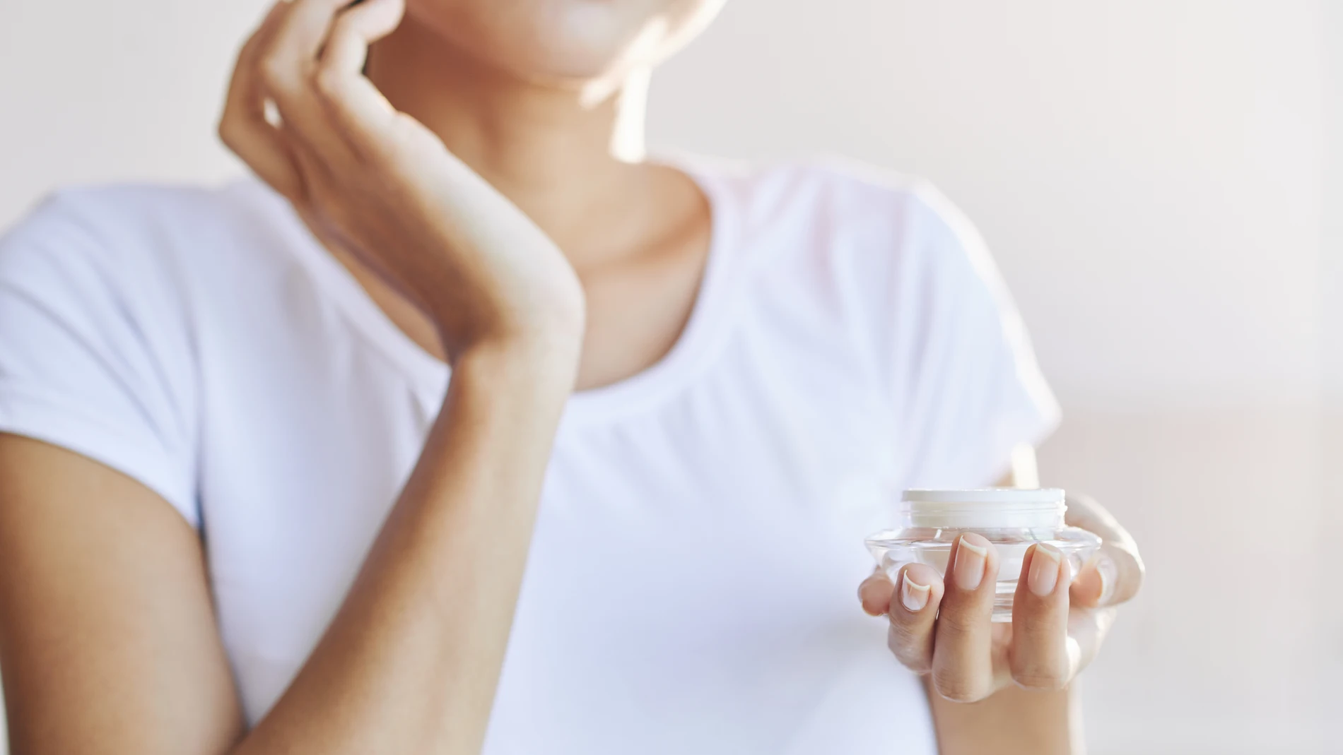 Mujer extendiendo crema hidratante en el rostro, rutina de belleza.