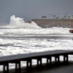 Un hombre mira como las olas rompen en las rocas del paseo marítimo de Torrevieja (Alicante), dentro del temporal de lluvia y viento en el sudeste de la Península ibérica