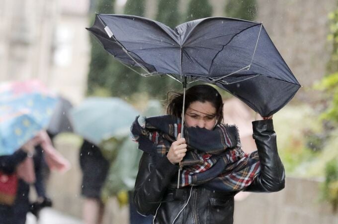 Una mujer combate los fuertes vientos y la lluvia