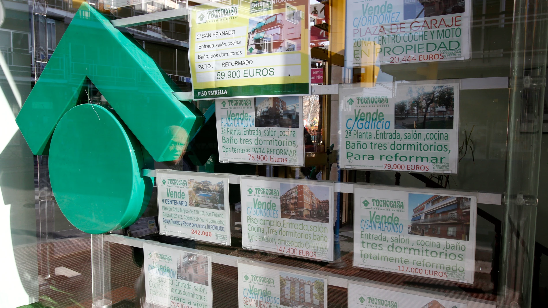 Numerosos carteles de venta de pisos ocupan el escaparate de una entidad inmobiliaria