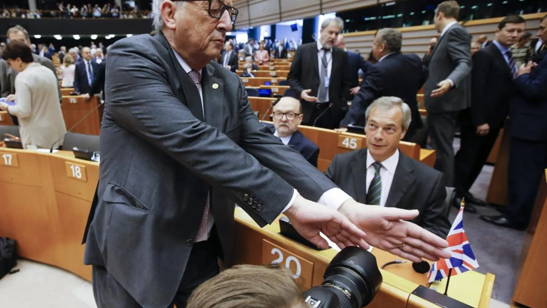 Juncker (i), intenta tapar la cámara a un fotógrafo que enfoca al líder del Partido de la Independencia de Reino Unido (UKIP), Nigel Farage (d)