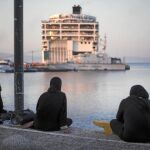 Tres mujeres observan desde la costa el crucero amarrado en la isla de Kos.