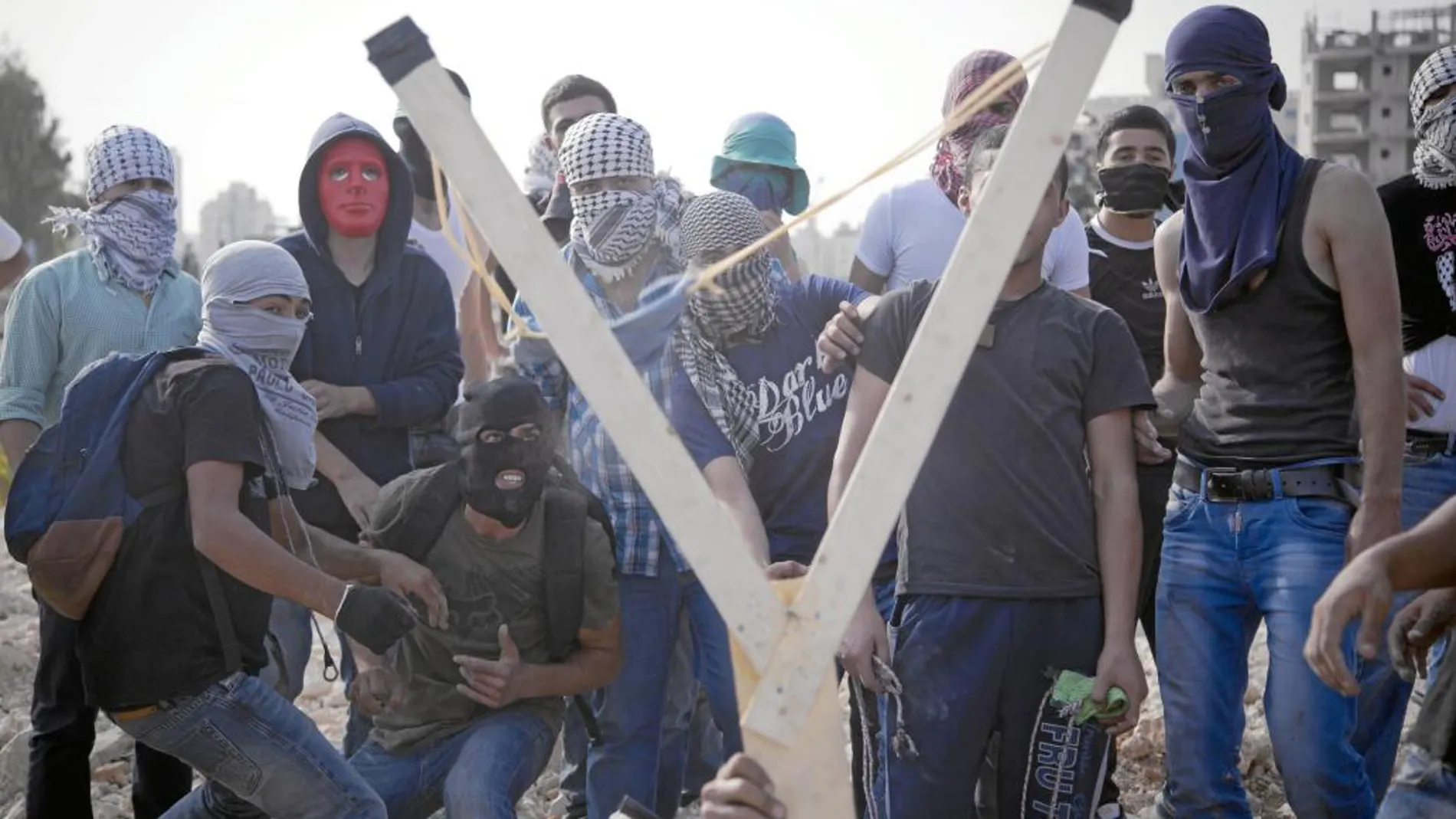 Palestinos lanzan piedras con un tirachinas casero, cerca de Ramala
