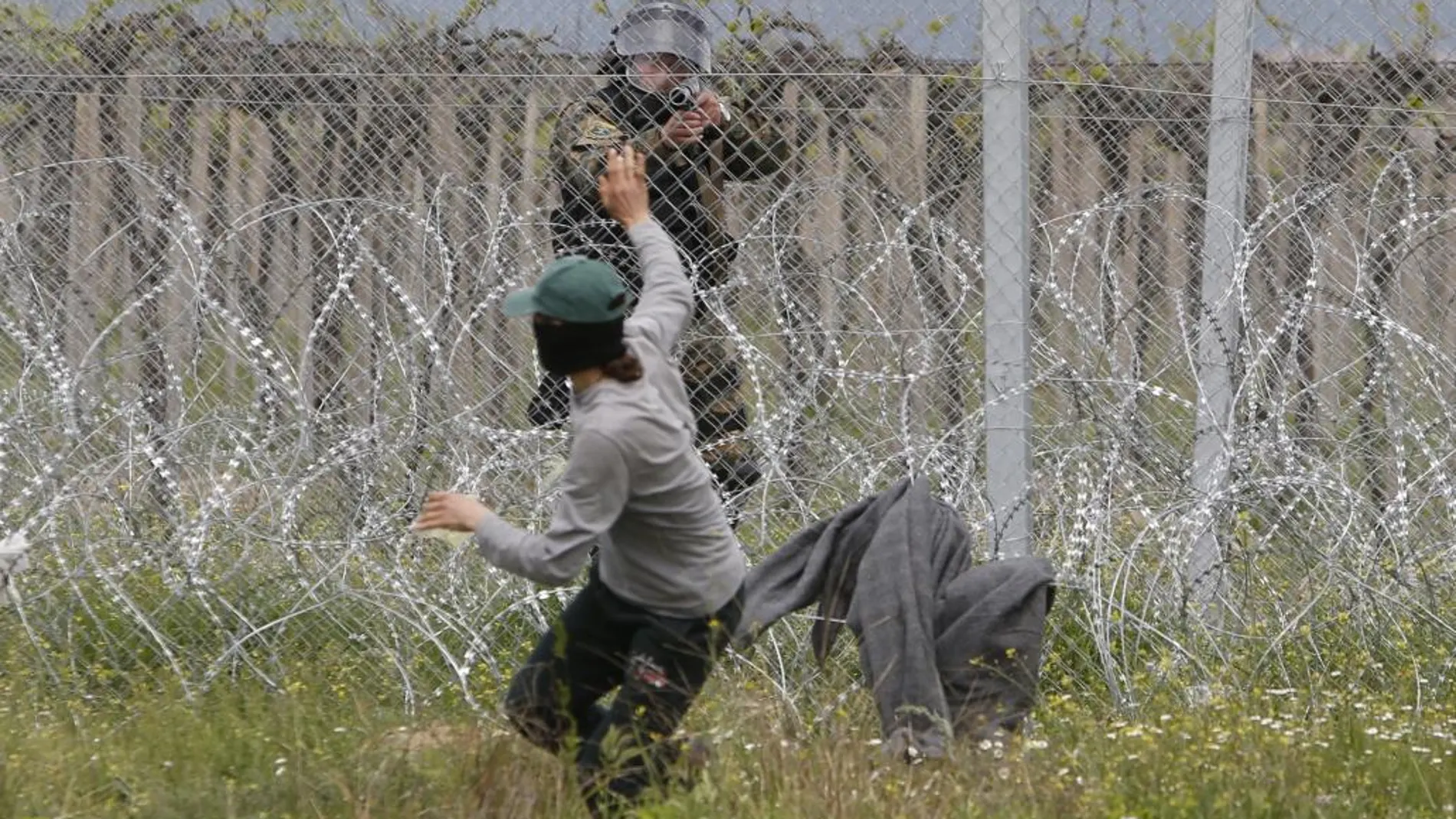 Un Policía apunta con su arma a un refugiado en la frontera de Idomeni