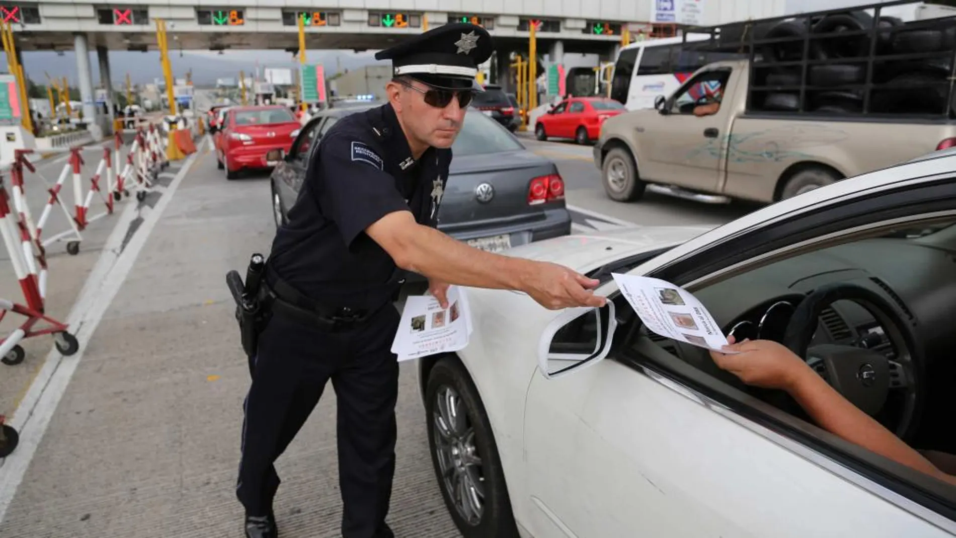 Fotografía cedida por la Policía Federal que muestra a un policía mientras distribuye folletos a los conductores donde se anuncia la recompensa de 60 millones de pesos