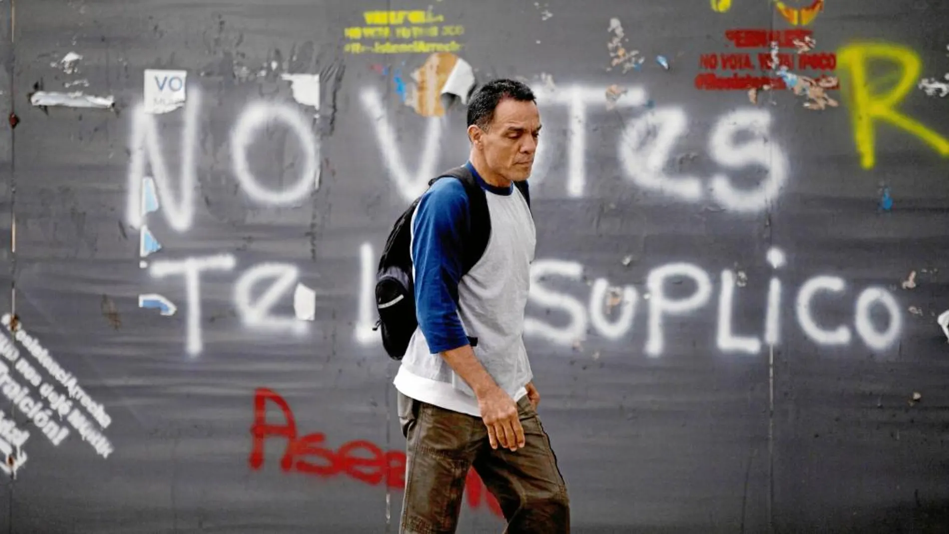 Un hombre pasa junto a una pintada que pide la abstención para las elecciones del 20 de mayo