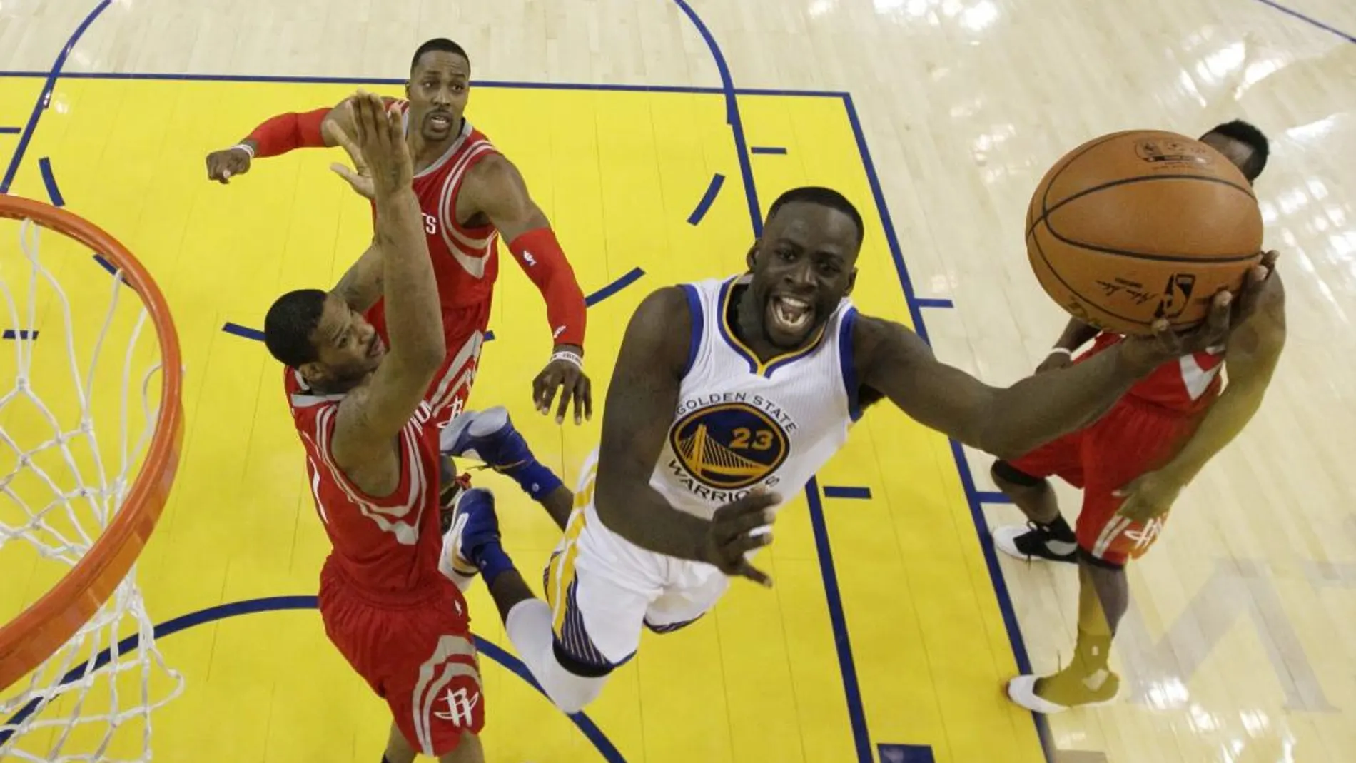 El jugador de los Warriors de Golden State Draymond Green (c) entra a canasta ante varios jugadores de los Rockets de Houston