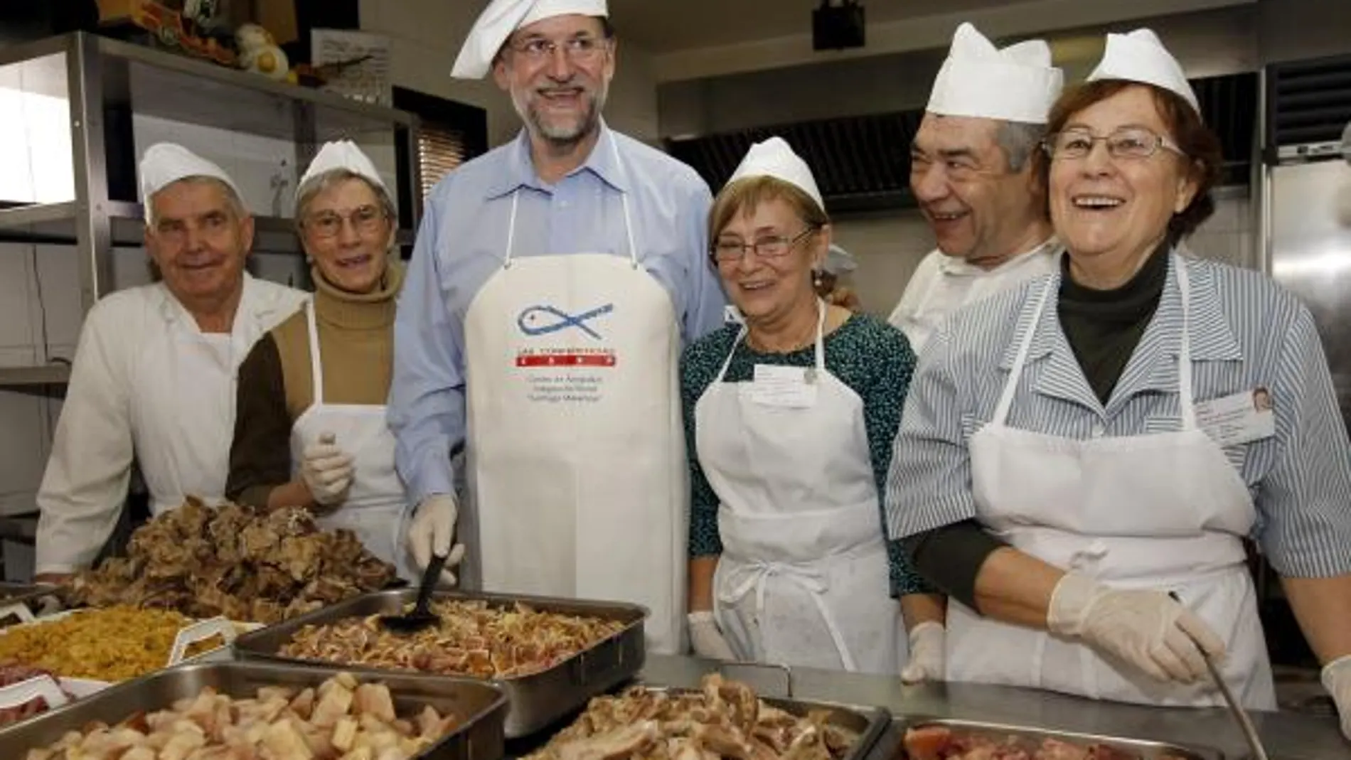 Fotografía facilitada por el PP de su presidente, Mariano Rajoy, junto a trabajadores y voluntarios del comedor social "Santiago Masarnau"a donde por tercer año consecutivo, Rajoy ha acudido como voluntario y ha ayudado a preparar y posteriormente a ser