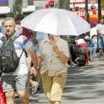 Una mujer se protege del fuerte sol bajo un paragüas en pleno centro de Barcelona