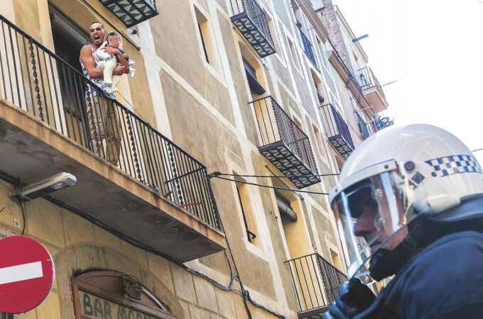 En la imagen, uno de los ocupas protestando por el desalojo en la calle San Ramón del Raval con un niño en brazos.