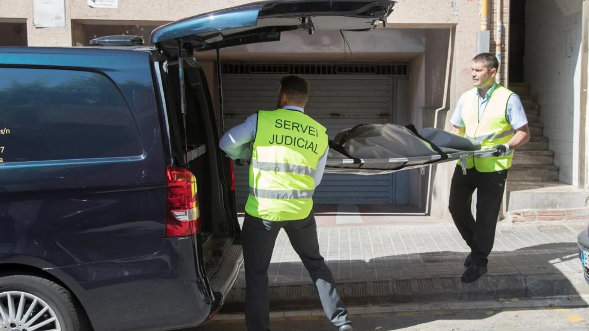 Miembros del servicio judicial retiran el cadáver de la mujer que ha sido asesinada presuntamente por su pareja en su domicilio de Badalona / Foto: Efe