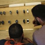 Dos hombres observan varias unidades del reloj inteligente de Apple, Apple Watch, que ha salido a la venta hoy en España.