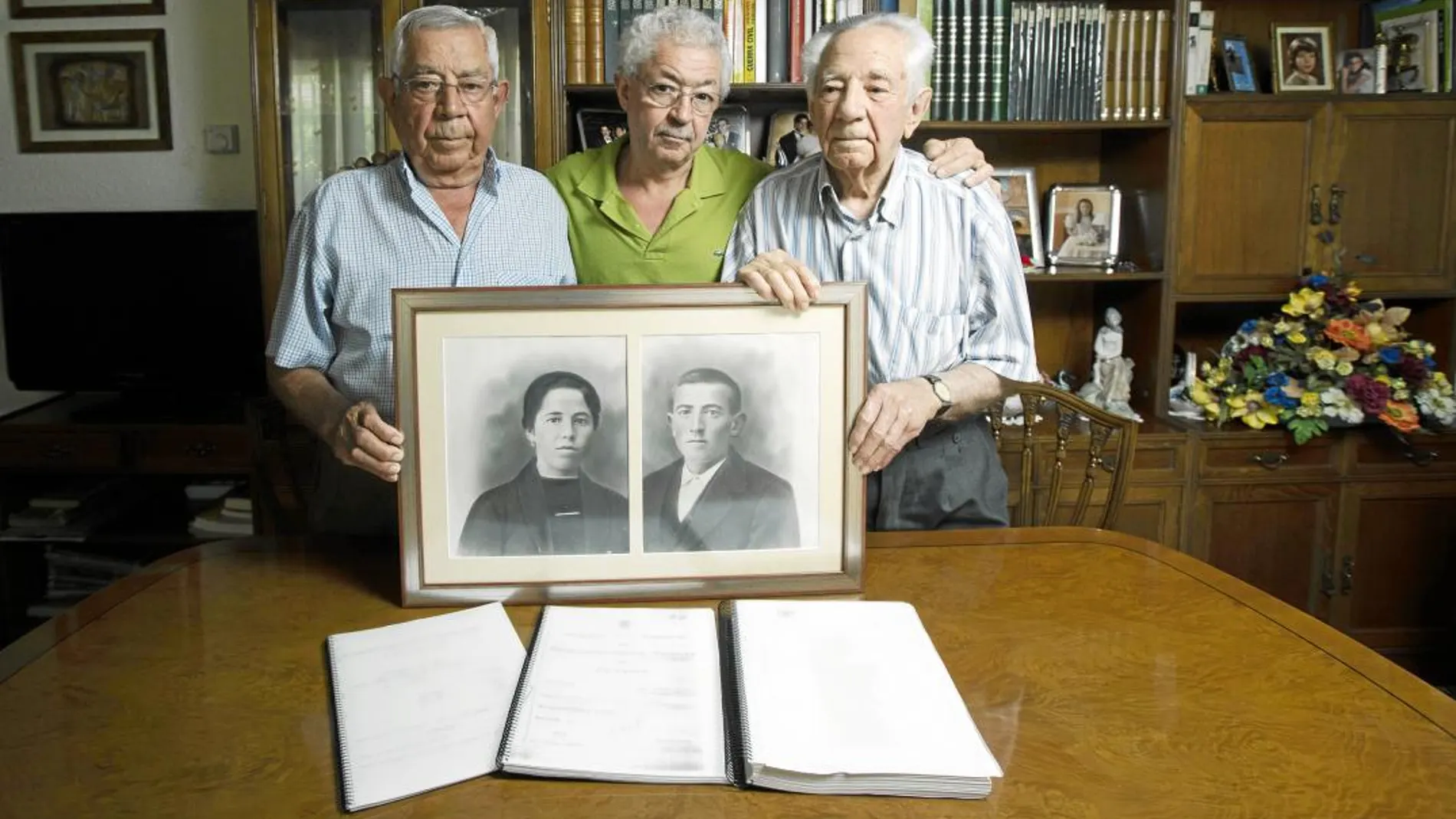Jesús Cansado (86), su hijo Francisco (57) y su hermano mayor Pascual (95) posan junto al retrato de su padre, José Cansado, fusilado en 1936, y su madre, Manuela. Foto: Jesús G. Feria