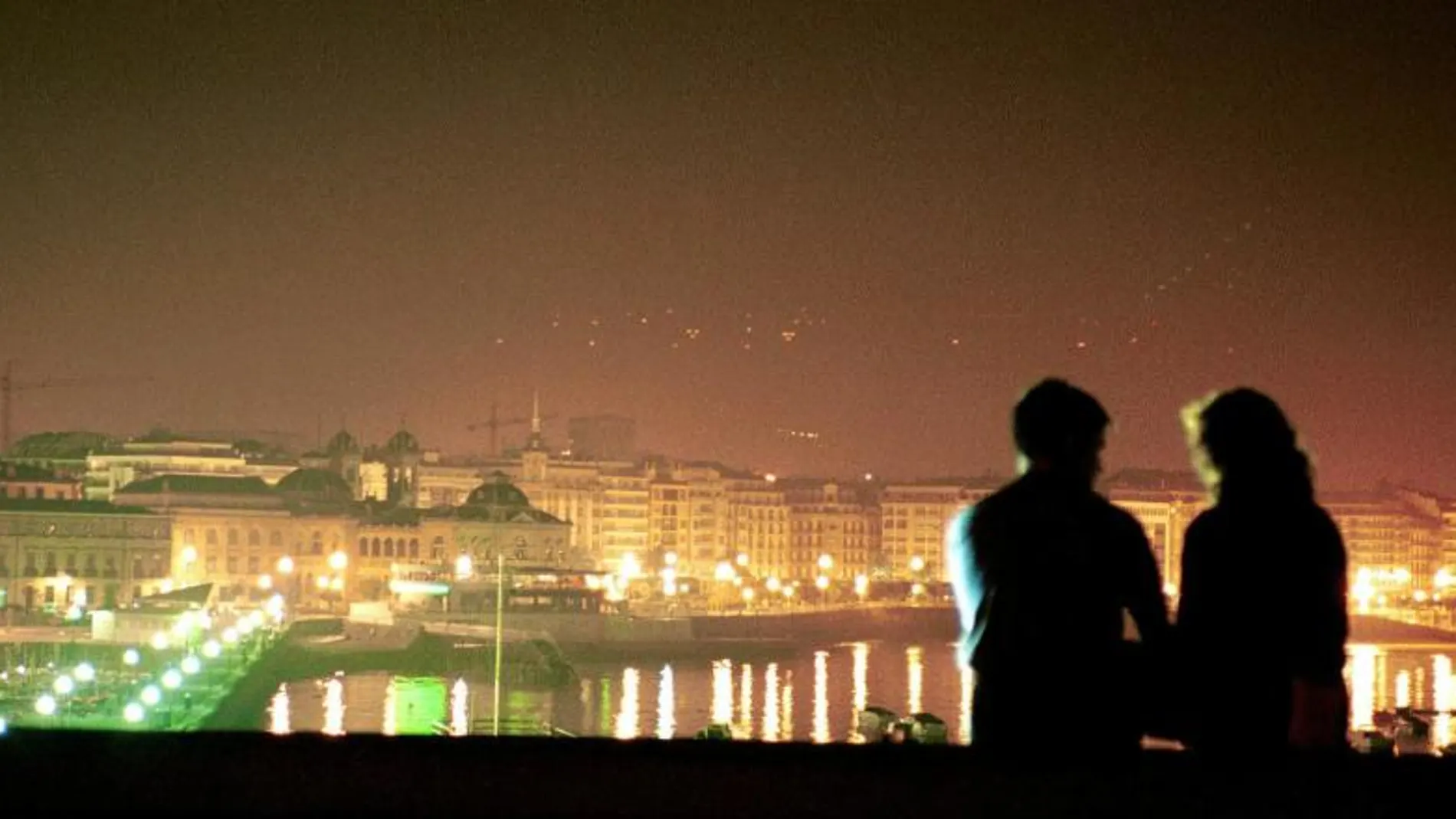 Una pareja disfruta de la vista nocturna de la ciudad de San Sebastián desde el Aquarium.