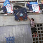 Un niño juega al baloncesto en una cancha plagada de pósters con el rostro de Hugo Chávez, en Caracas