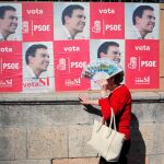 Una señora se protege del sol ayer en Ronda delante de un carte electoral socialista abogando por el cambio
