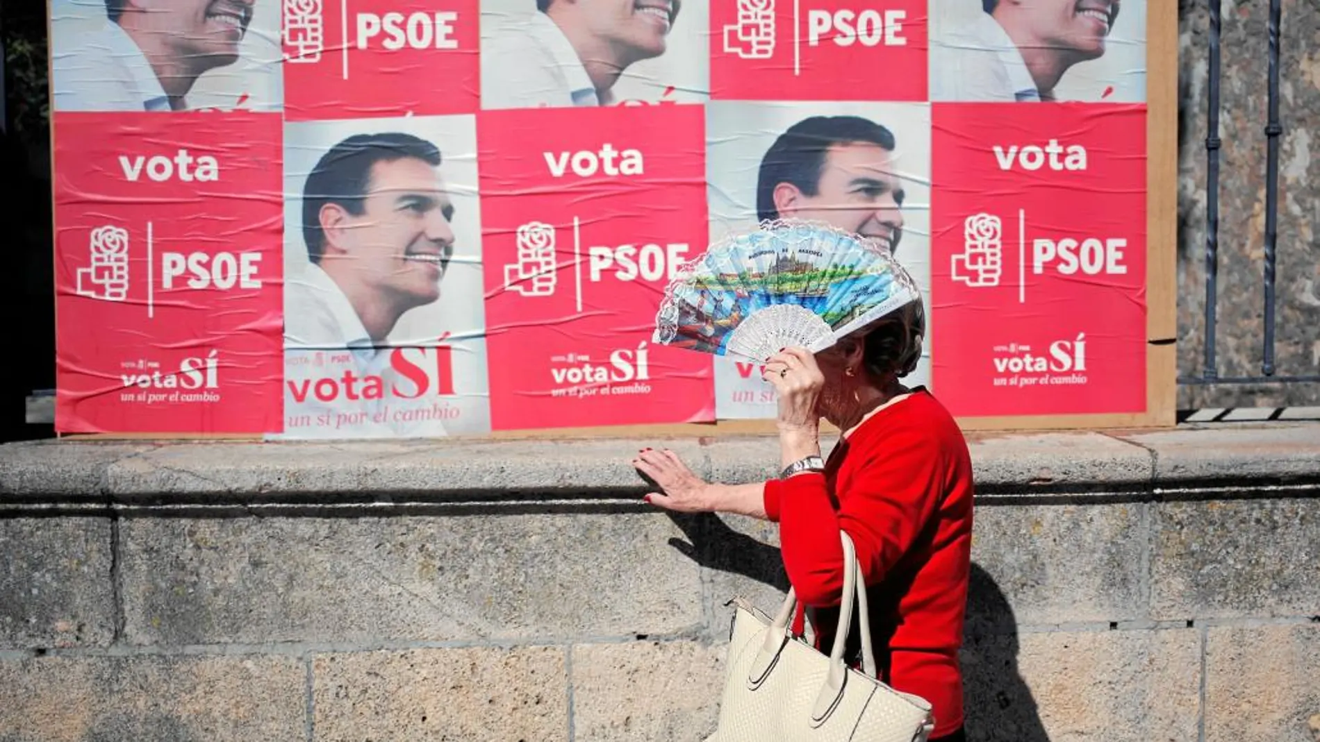Una señora se protege del sol ayer en Ronda delante de un carte electoral socialista abogando por el cambio