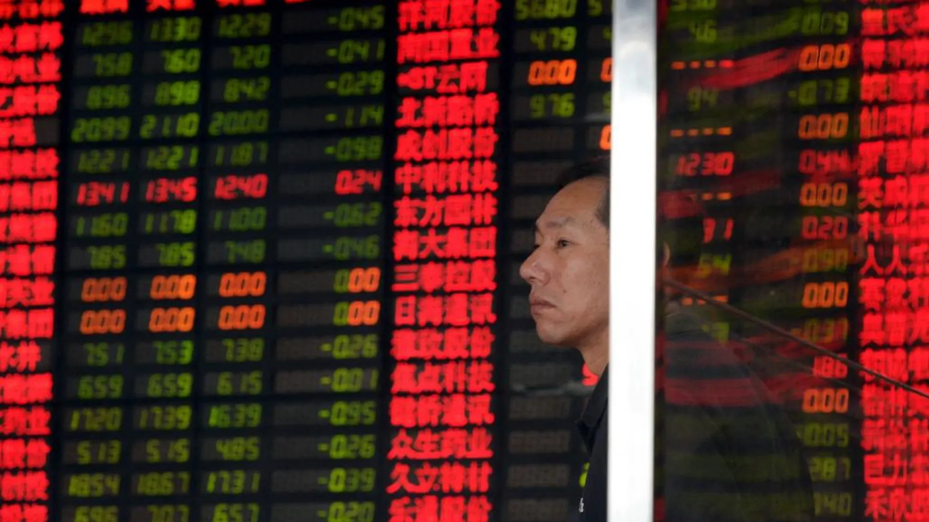 Un inversor contempla un panel con valores en la bolsa de Shangai.