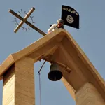 Un yihadista retira la cruz de una iglesia para sustituirla por la bandera del Estado Islámico. Foto extraída de la revista «Dabiq», que editaba el grupo terrorista