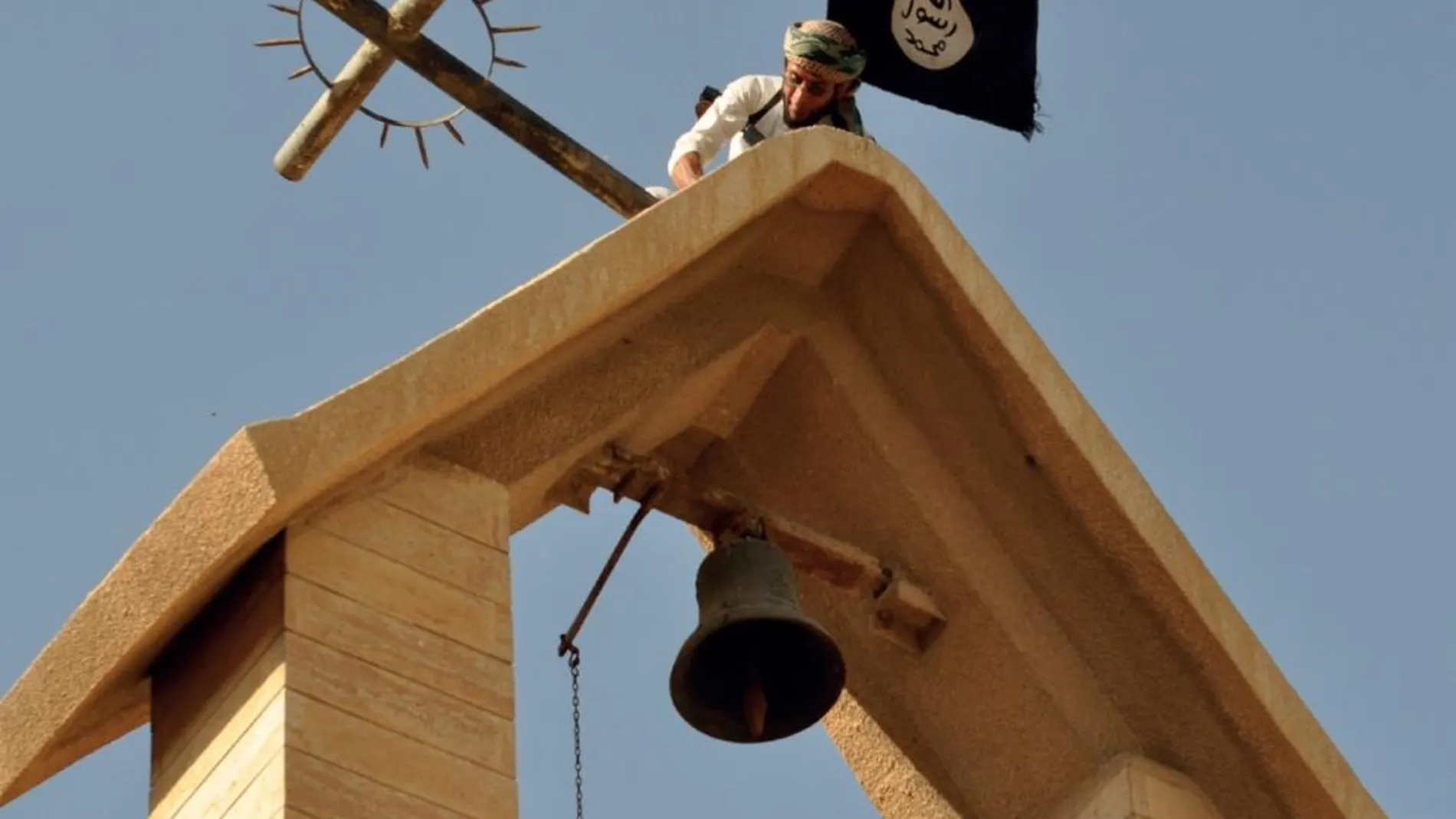 Un yihadista retira la cruz de una iglesia para sustituirla por la bandera del Estado Islámico. Foto extraída de la revista «Dabiq», que editaba el grupo terrorista
