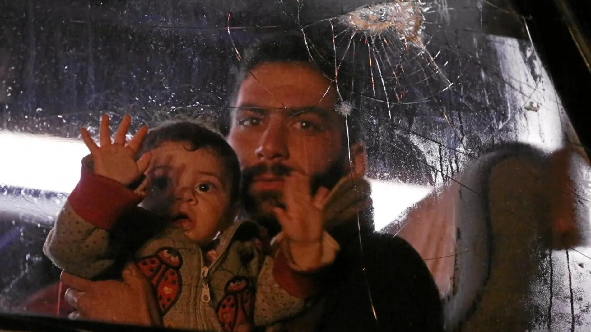 Un civil de la ciudad siria de Duma sostiene en brazos a un bebe en el autobús que le trasladará a Alepo