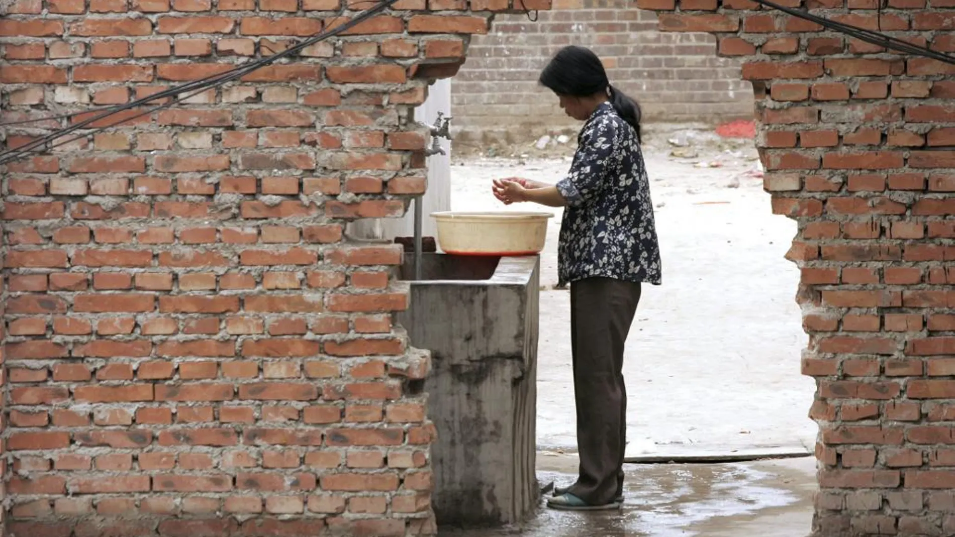 Una mujer se lava las manos en un barreño de agua en Pekín (China)