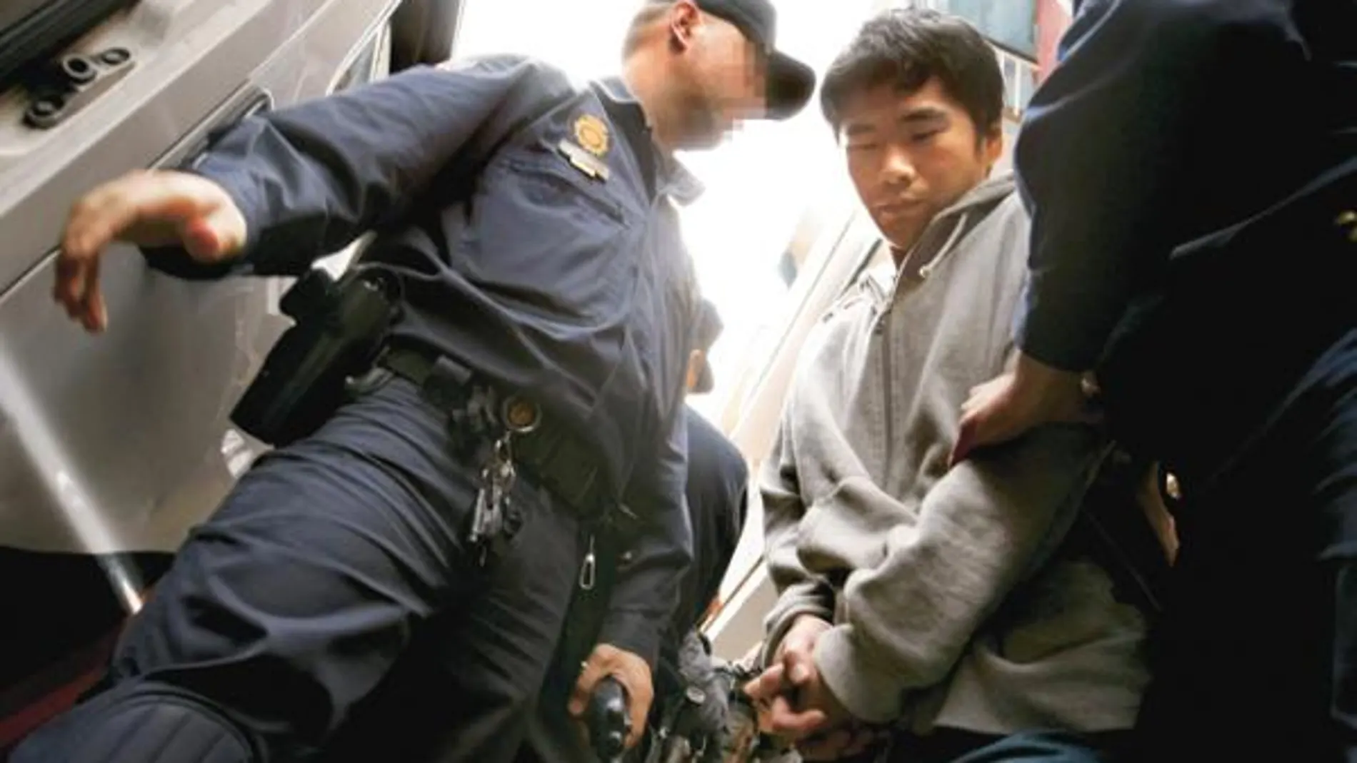 Dos agentes custodian a uno de los inmigrantes detenidos en la operación