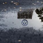El logotipo de Volkswagen se refleja en un charco en el parking de empleados de la compañía en Wolfsburgo