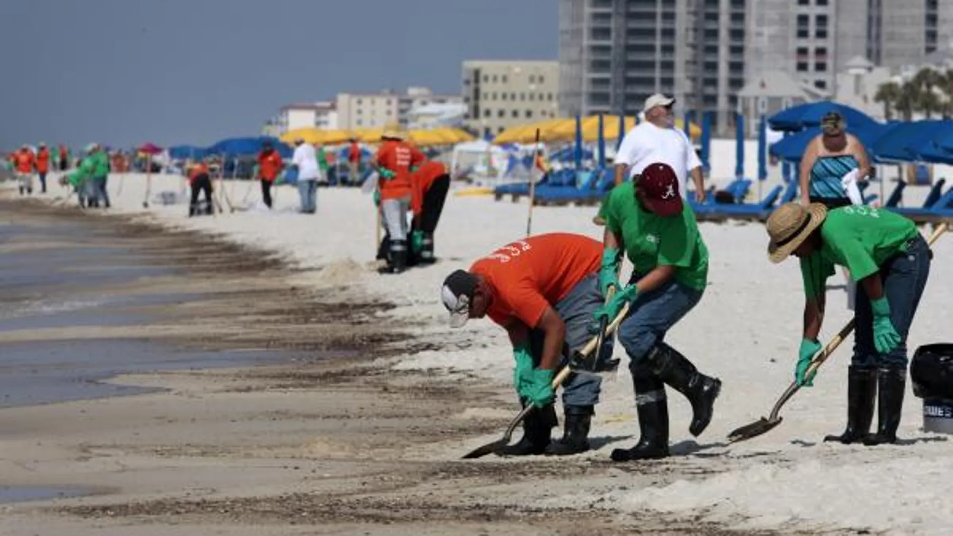 Voluntarios intentan limpiar manchas de crudo en una playa de Alabama