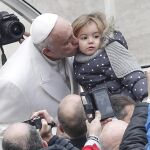 El Papa besa a una niña a su llegada a la audiencia general jubilar celebrada en el Vaticano