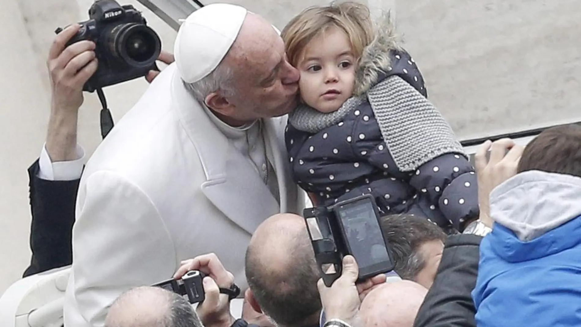 El Papa besa a una niña a su llegada a la audiencia general jubilar celebrada en el Vaticano