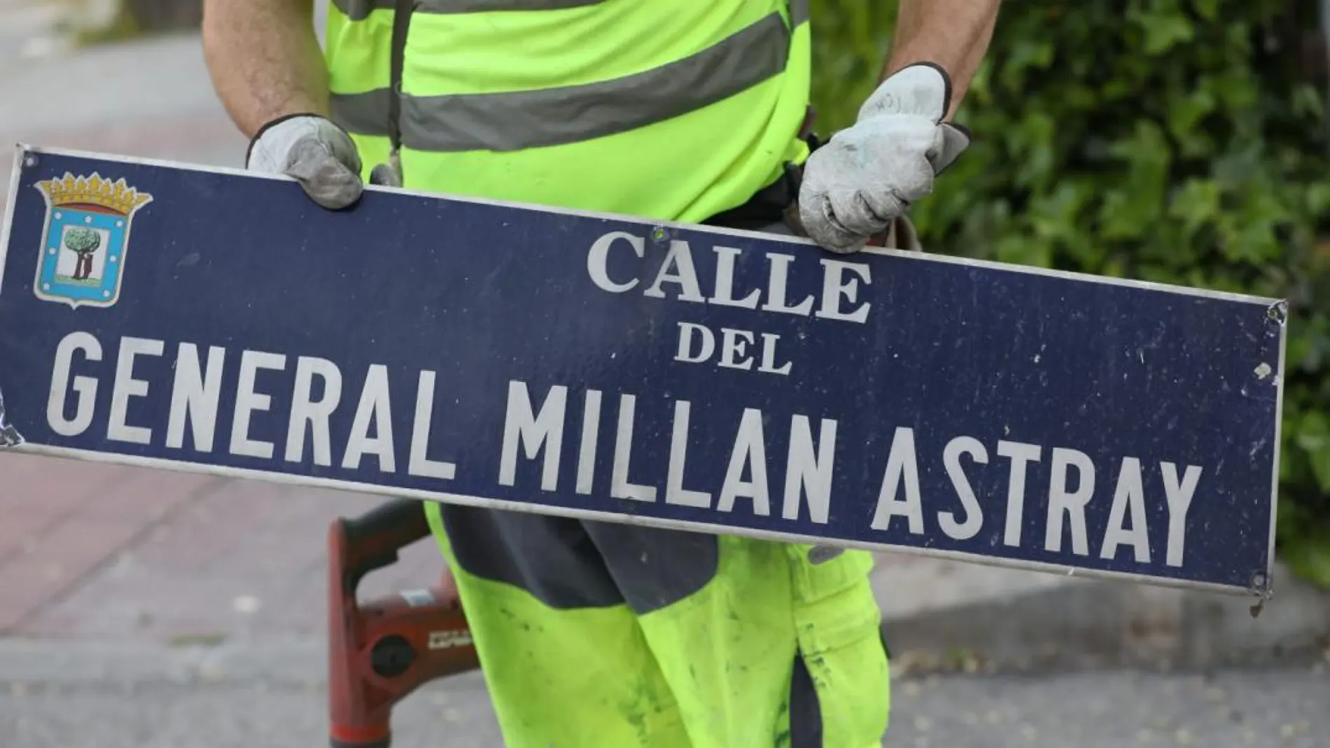 Un operario desmontando la placa de una de calles franquista