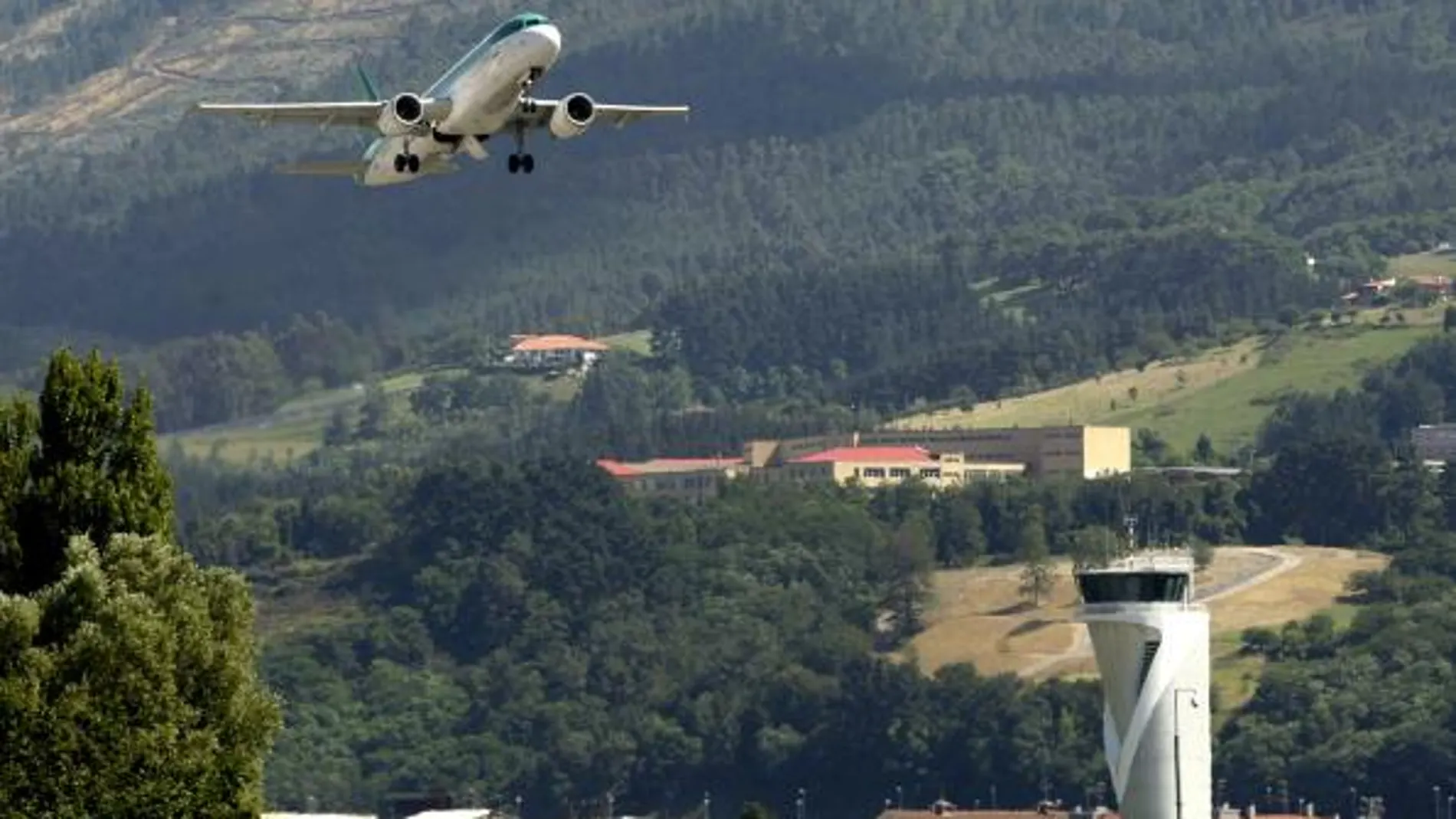 Un avión despega esta tarde ante la torre de control del aeropuerto de Bilbao