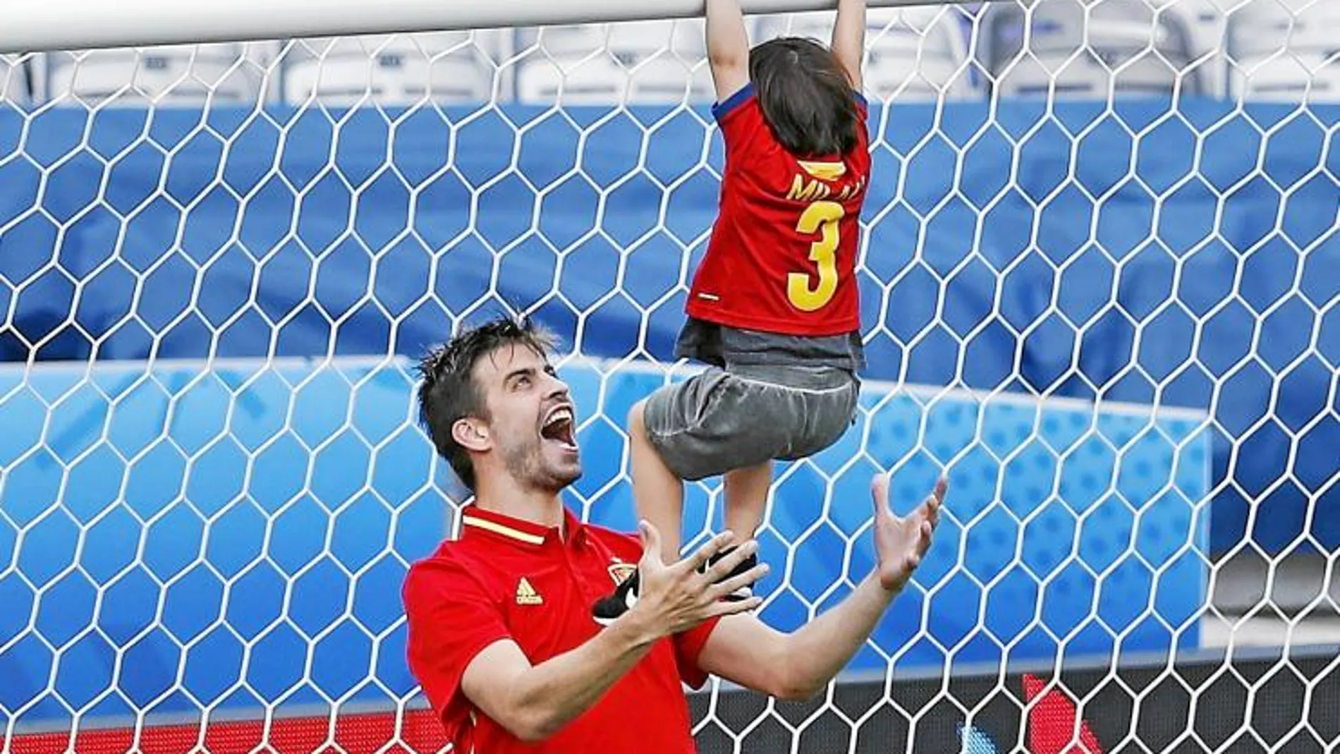 Piqué con su hijo Milan sobre el césped al terminar un partido de España
