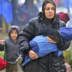 Una mujer camina con su hijo en brazos bajo la lluvia mientras en la frontera entre Croacia y Eslovenia en Trnovec (Croacia)