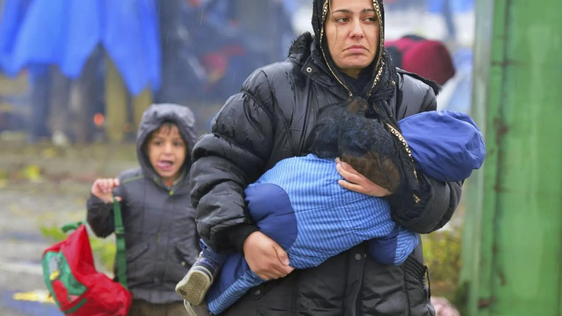 Una mujer camina con su hijo en brazos bajo la lluvia mientras en la frontera entre Croacia y Eslovenia en Trnovec (Croacia)
