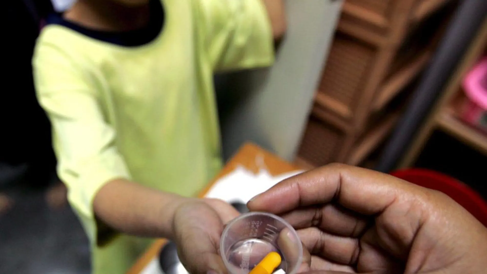 Un huérfano seropositivo recibe medicación anti-retroviral en el centro Mercy de Bangkok (Tailandia)