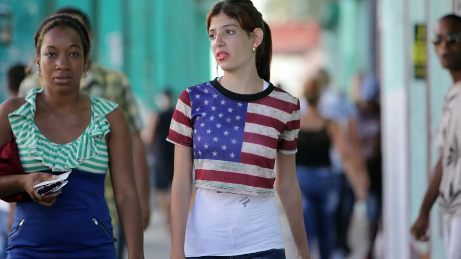 Una joven cubana con una camiseta de la bandera de Estados Unidos camina en La Habana (Cuba)