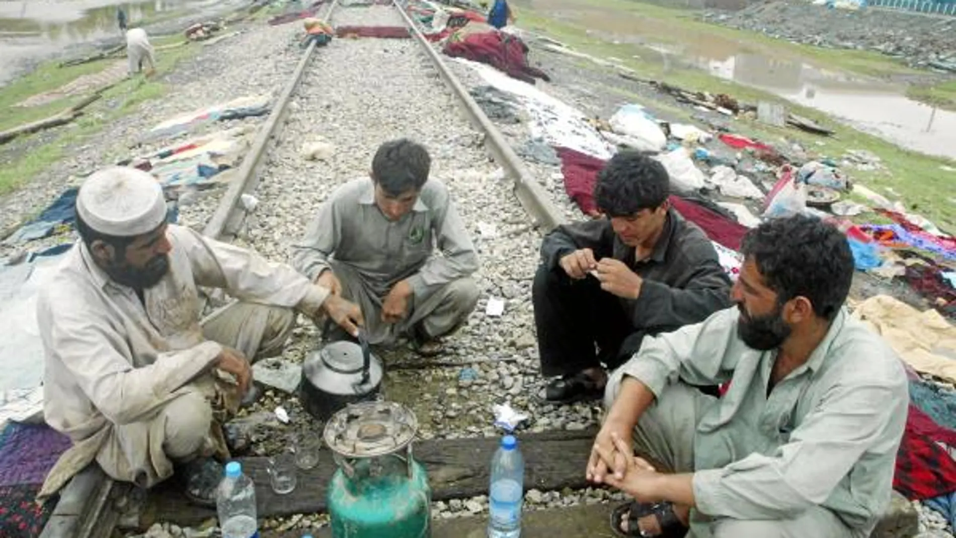 Víctimas de las inundaciones se sientan en una vía férrea para tomar un té en la localidad de Nowshera