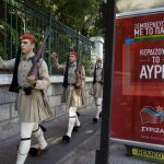 Soldados de la guradia presidencial griega desfilan junto a un cartel electoral de Syriza