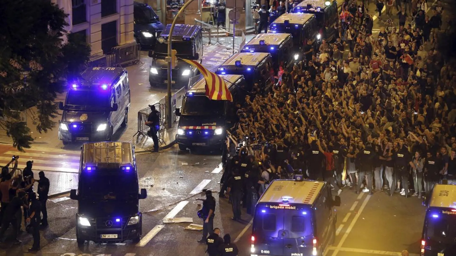 Miembros de los Mossos de Escuadra escoltan la salida de varias furgonetas de la Policía Nacional de la jefatura Superior de Policía de Barcelona