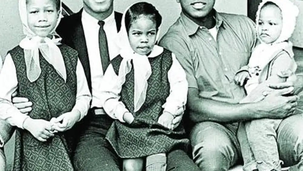 Malcolm X fotografiado con tres de sus hijas junto a Cassius Clay un año antes de su muerte. El boxeador sostiene en sus brazos a Ilyasah