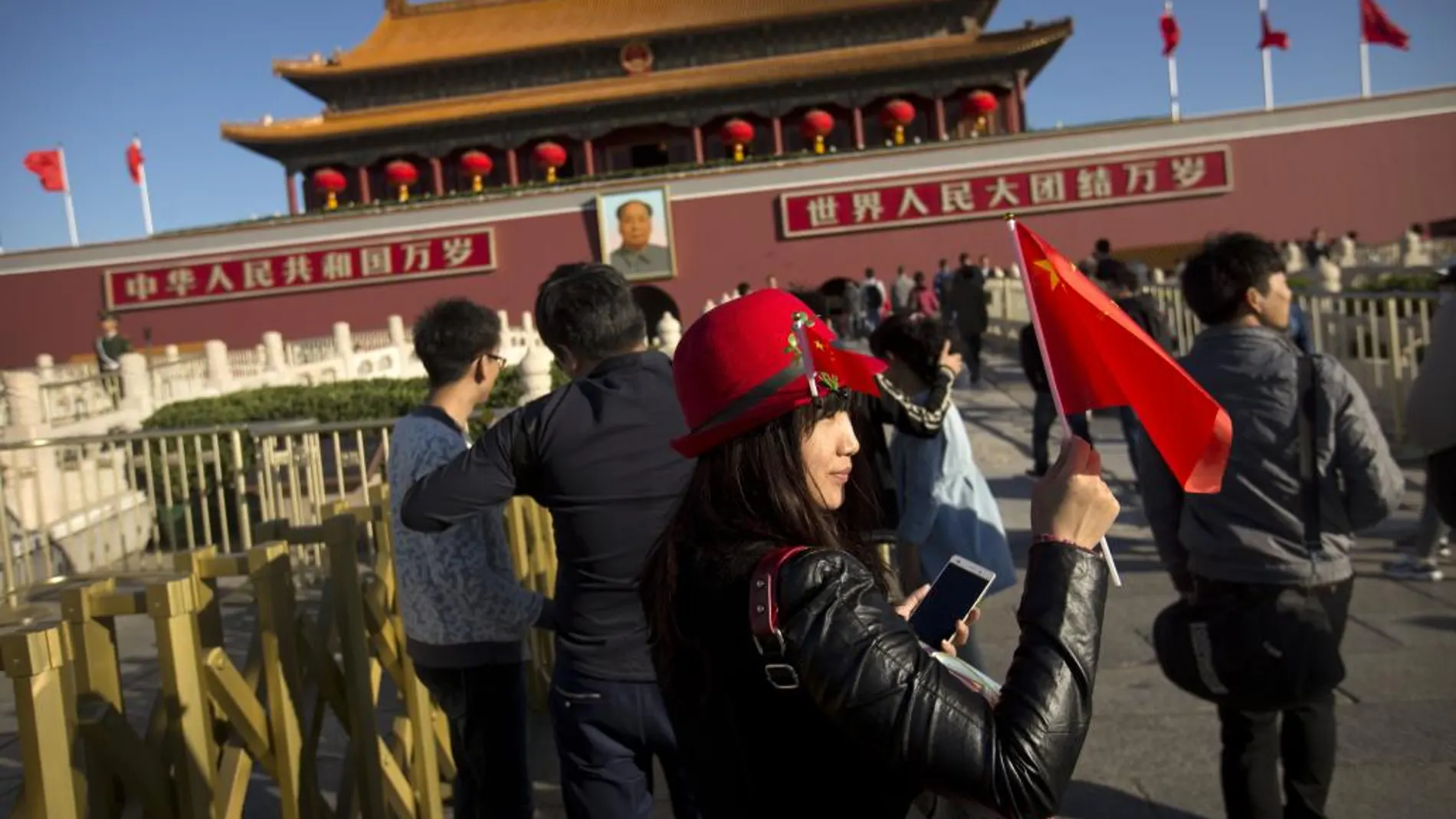 Una mujer agita una bandera mientras posa para una foto en la plaza de Tiananmen