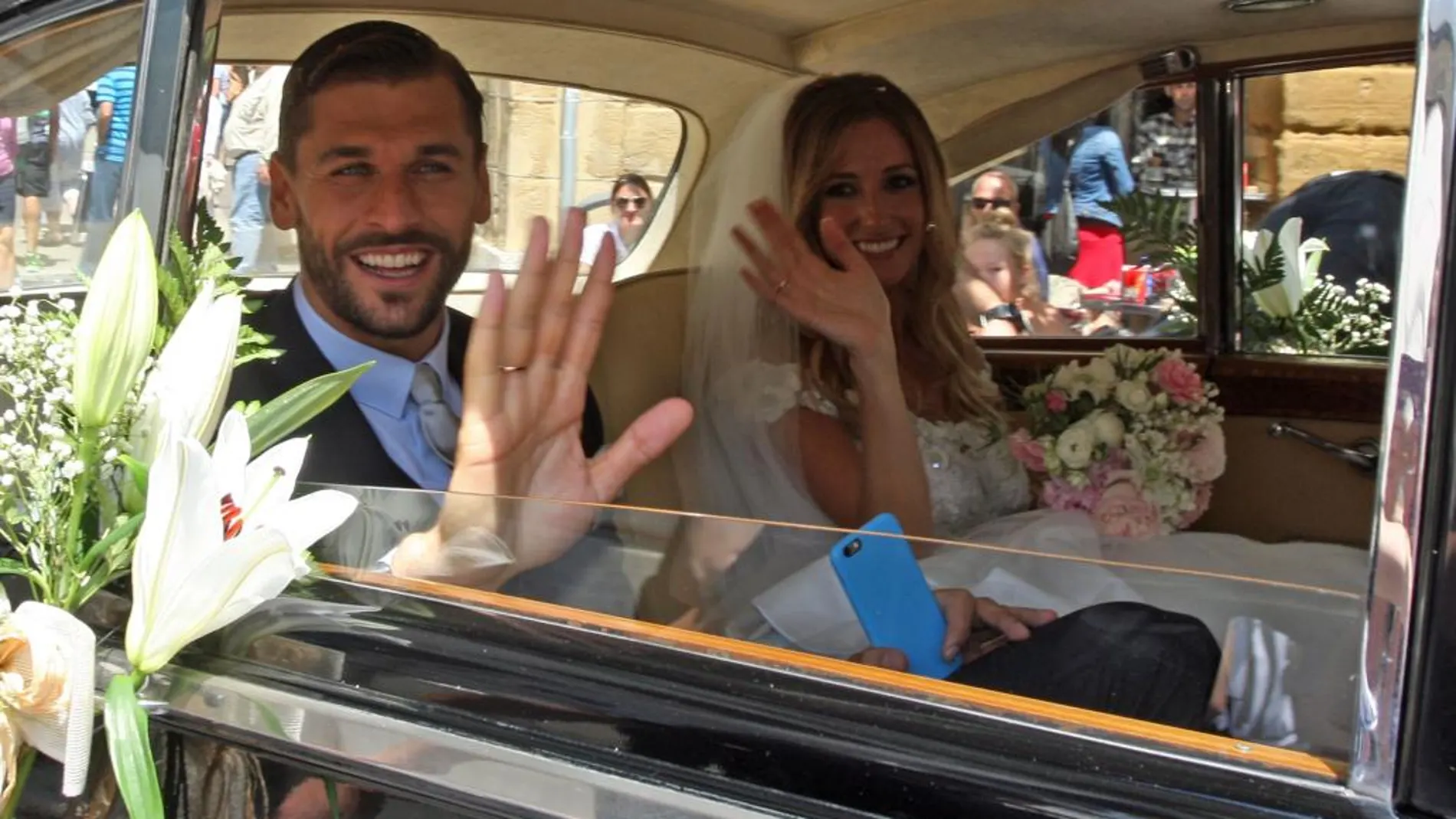 Los recién casados saludad desde el Rolls-Royce en el que han abandonado el lugar