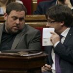 El presidente de la Generalitat, Carles Puigdemont (d) conversa con el vicepresidente Oriol Junqueras (i)