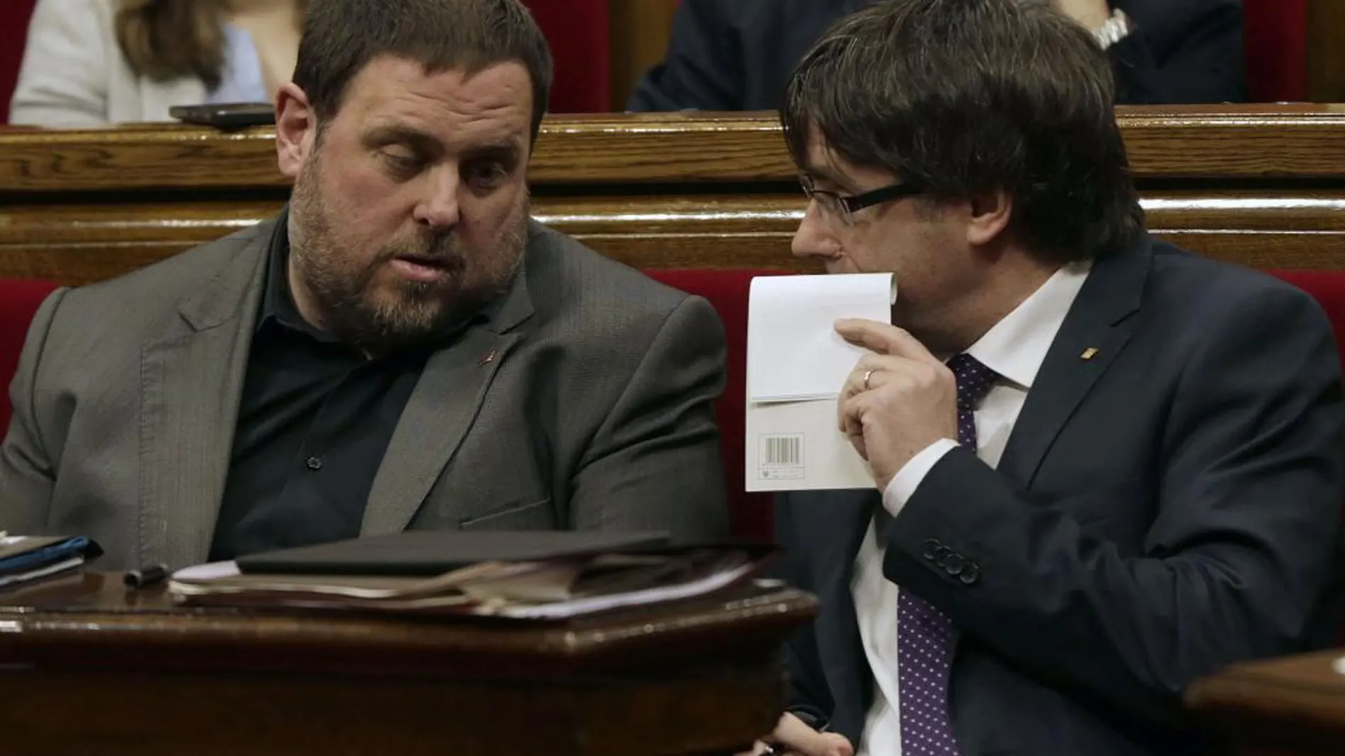 El presidente de la Generalitat, Carles Puigdemont (d) conversa con el vicepresidente Oriol Junqueras (i)